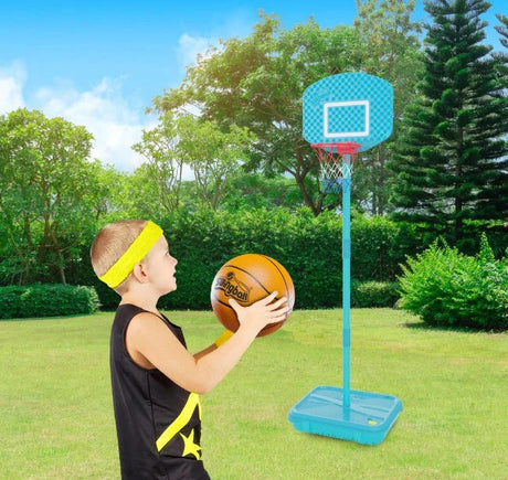 Child holding an orange basketball beside a turquoise Mookie basketball hoop on grass