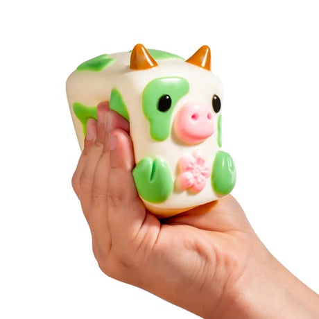 MushyKinz OG white and green cow Taba Squishy squeezed in one hand