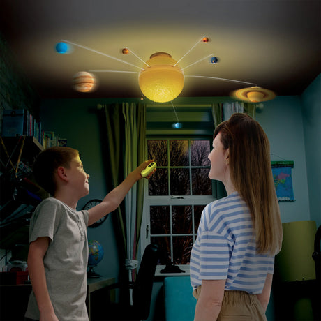 Child using remote control to activate My Very Own Solar System ceiling mobile with glowing planets and sun overhead
