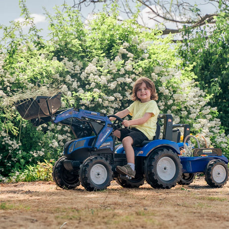 Child driving New Holland Blue backhoe with trailer in garden setting – Ireland