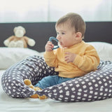 Baby chewing Nuvita blue teether while sitting on a patterned cushion