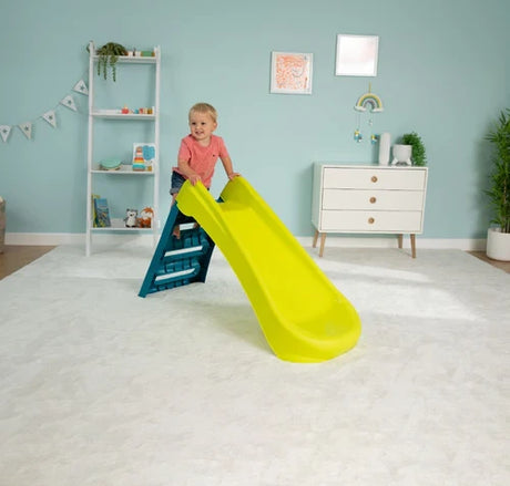 Child on the green and blue folding slide in a room
