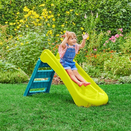 Child seated on the green and blue folding slide on grass