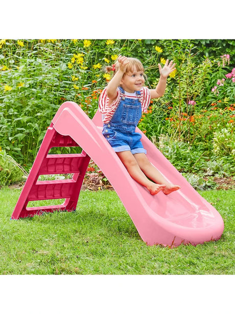 Child seated on the pink and redfolding first slide on grass
