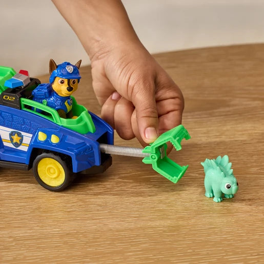 Hand operating the rescue claw on the PAW Patrol Chase Dino Rescue Cruiser beside the green dinosaur figure