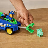 Hand operating the rescue claw on the PAW Patrol Chase Dino Rescue Cruiser beside the green dinosaur figure