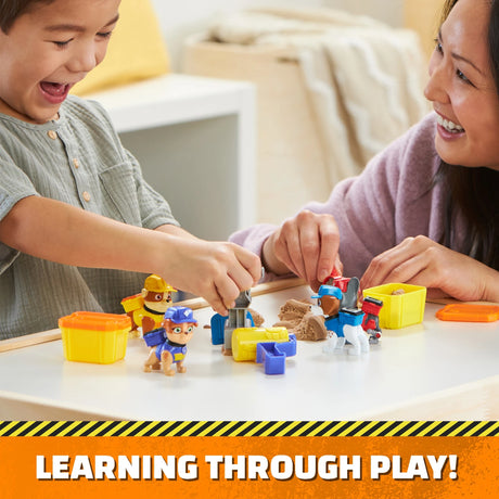 Children playing with Paw Patrol Rubble & Crew Build-It Figure Pack figures, sand tubs and tools on a table