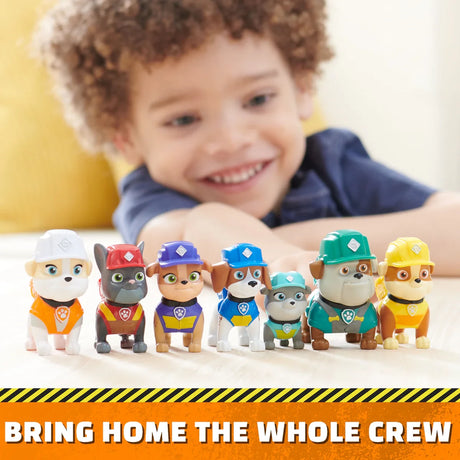 Paw Patrol Rubble & Crew figures lined up beside a child