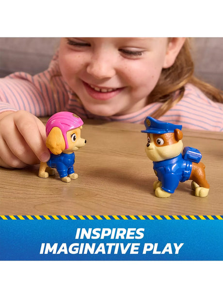 Child holding PAW Patrol Skye and Chase Search & Rescue figures on a table