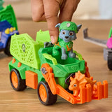 Hand placing Rocky in the driver's seat of the Dino Rescue Recycler with an orange dinosaur figure in the front claw