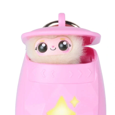 Close-up of the pink Peekimo interactive pet peeking out of its open pod, showing large glossy eyes, a smiling face, fluffy cream coloured fur and yellow illuminated star shapes.