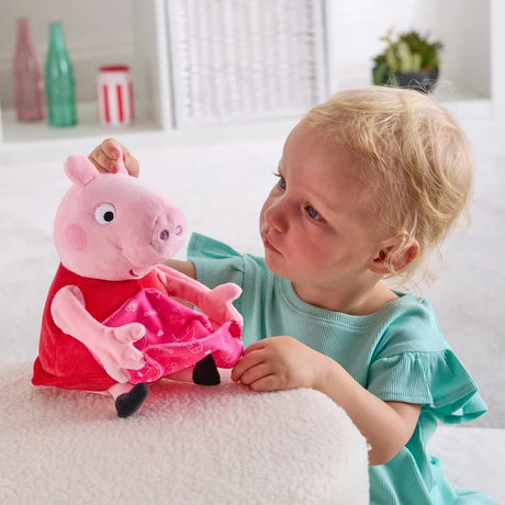 Child beside Peppa Pig soft toy with the pink blanket resting across Peppa's lap