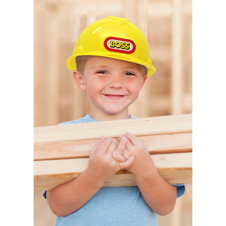Child wearing a yellow Boss construction helmet while holding wooden planks