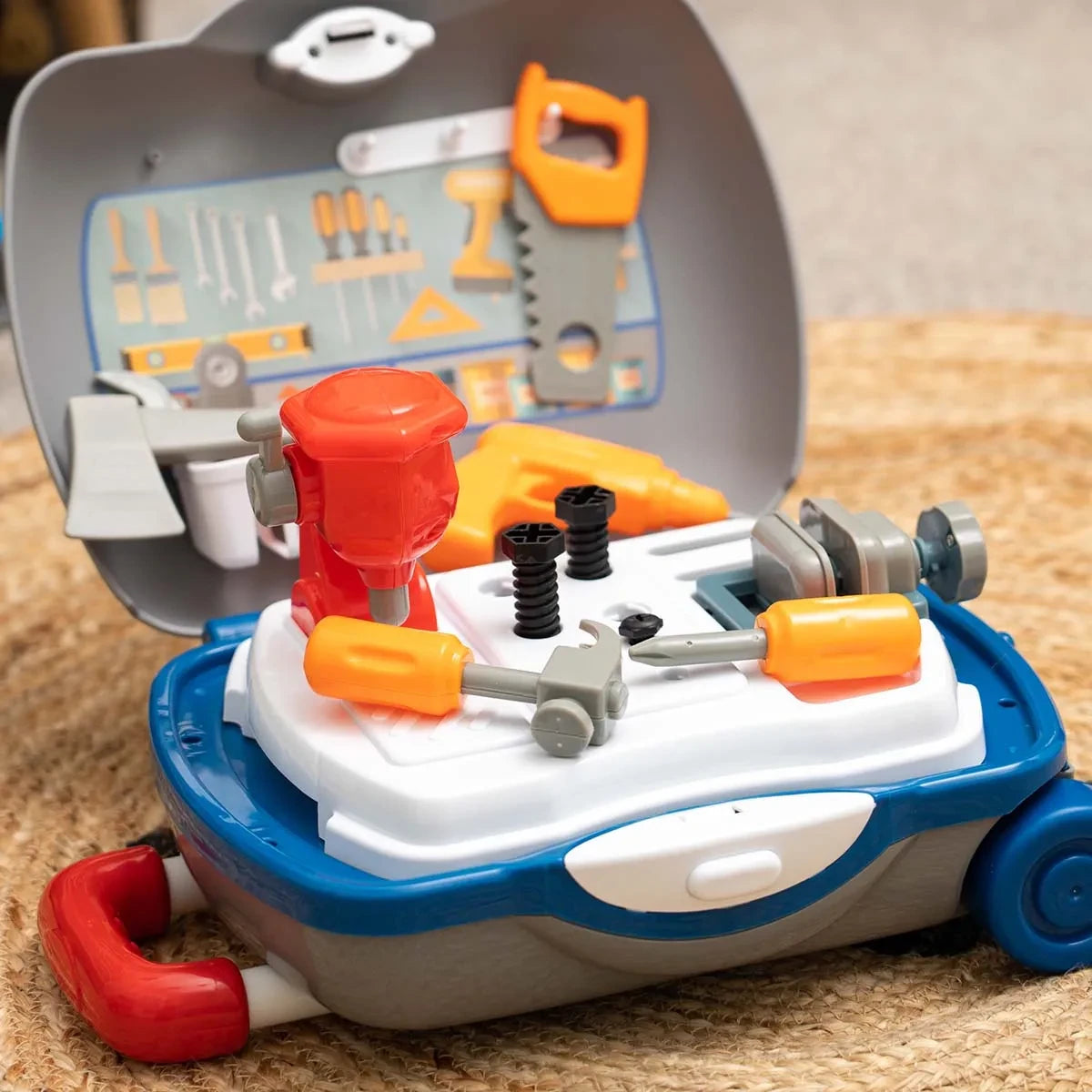 Open Little Workshop Suitcase with red bench drill, grey vice, orange saw, toy drill, hammer, screwdriver and two black bolts