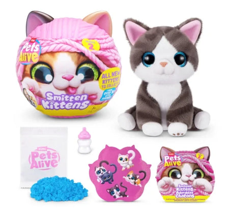 Pets Alive Smitten Kittens Series 2 white and brown plush kitten with blue eyes beside pink capsule, blue kinetic sand, milk bottle, sticker sheet and leaflet on white background