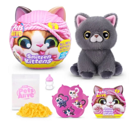 Pets Alive Smitten Kittens Series 2 grey plush kitten with gold eyes beside pink capsule, yellow kinetic sand, milk bottle, sticker sheet and leaflet on white background