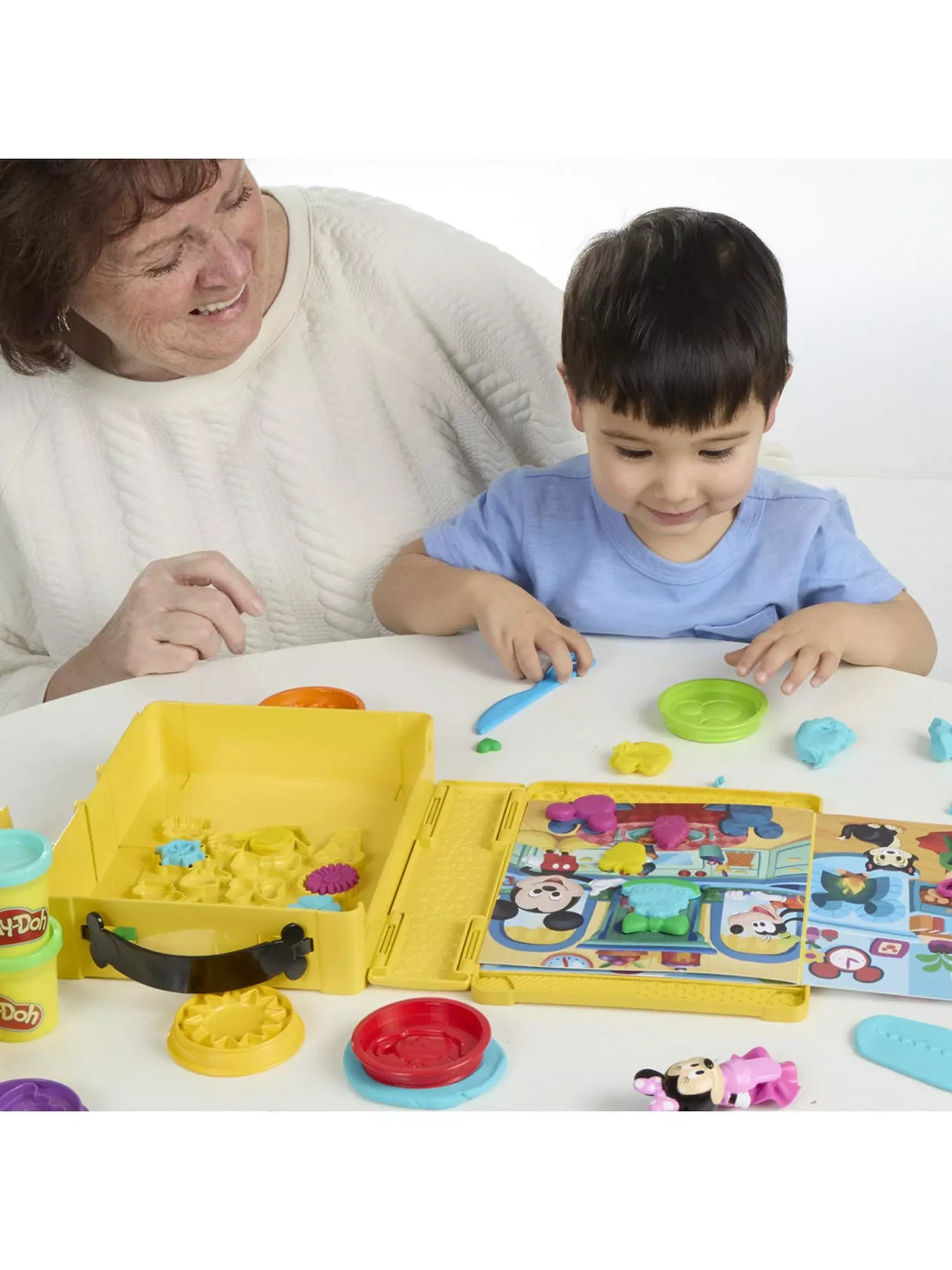 Child using the Play-Doh Disney Junior Shape A Story playset with open case, scene board and moulded shapes