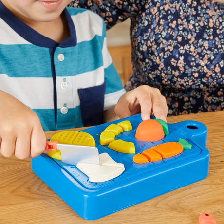 Child slicing Play-Doh shapes on blue cutting board – Ireland