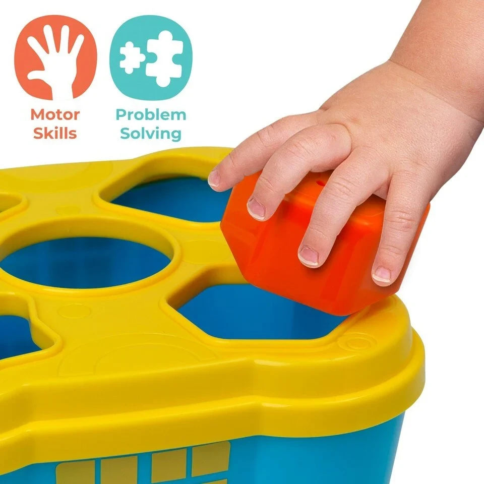 Child's hand holding an orange block over a shaped opening in the yellow lid of the blue castle base
