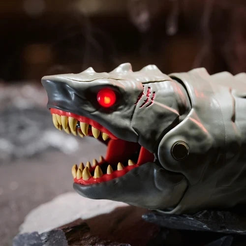 Close-up of the grey Primal Hatch Megalodon shark's head showing a glowing red eye, scar markings, open jaws, pointed yellow teeth and red mouth interior.