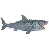 Full side view of the grey Primal Hatch Megalodon shark toy on a white background, showing its segmented body, dorsal fin, tail, side fins, red eye and open mouth with pointed teeth.