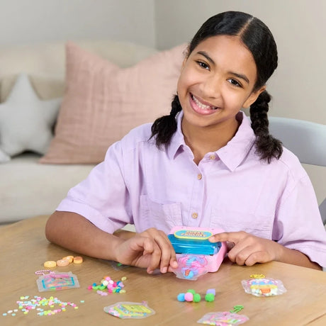 Girl using the Puffy Pouches laminator with candy themed pouches and decorations arranged on the table