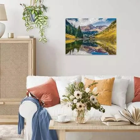 Completed Ravensburger Aspen Colorado puzzle displayed on a living room wall above a white sofa