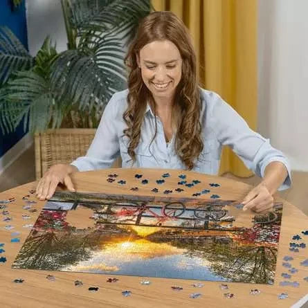 Person building the Bicycles of Amsterdam puzzle on a wooden table