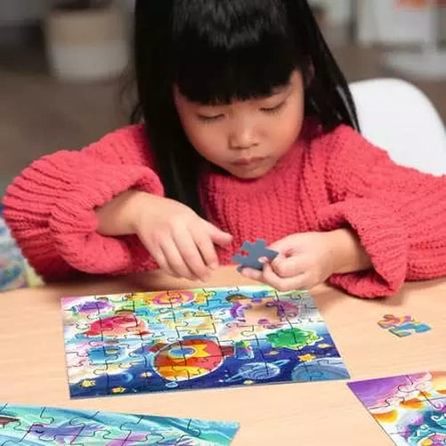 Child assembling a Ravensburger Candy Coastline jigsaw puzzle on a table with loose pieces and finished sections nearby