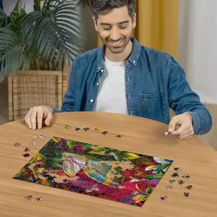 Person building the Chameleon puzzle on a round wooden table