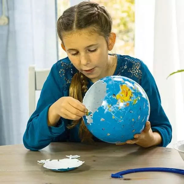 Ravensburger Children’s World Map 3D Puzzle being assembled by a child with curved puzzle pieces and stand components on the table