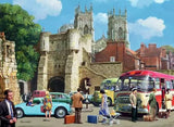 Ravensburger Day Out in York puzzle artwork showing a busy historic York street with stone gateway, vintage cars, coach, pedestrians and cathedral towers
