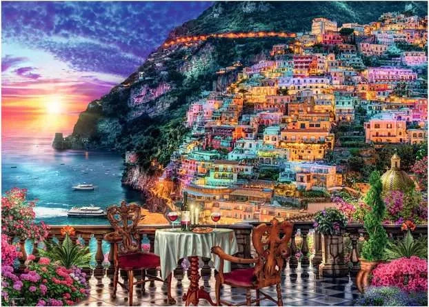 Ravensburger Dinner in Positano puzzle artwork showing a sunset over the sea, colourful hillside buildings and a dinner table on a flower filled terrace
