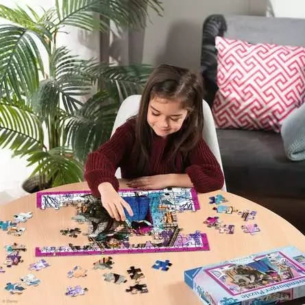 Child assembling the Ravensburger Disney Frozen jigsaw puzzle on a table with loose pieces and the puzzle box nearby
