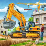 Yellow excavator at a building site with a crane and construction workers