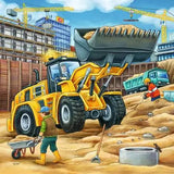 Yellow wheel loader on a construction site with workers and cranes in the background