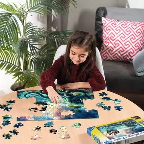 Child assembling the Ravensburger Octopus Treasure jigsaw puzzle on a table with loose pieces around the ocean scene