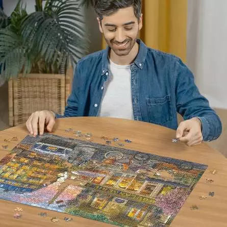 Ravensburger Paris at Dawn 1000 piece jigsaw puzzle in progress on a table with a person placing pieces