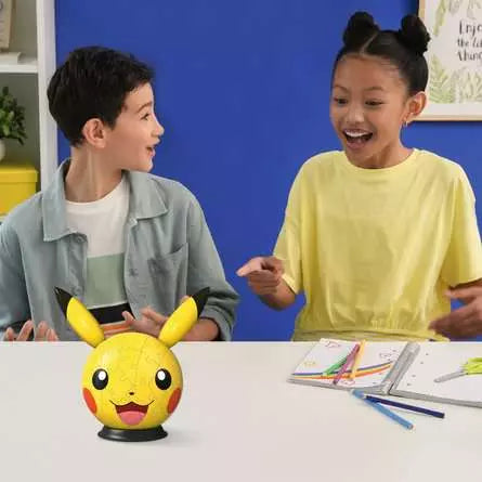 Ravensburger Pokémon Pikachu with Ears 3D Puzzle Ball on a table with two children looking at the completed puzzle
