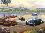 Ravensburger Stop at the Lakes puzzle artwork showing a vintage green car beside a lake with rowing boats, sailing boats and mountains