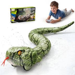 Green remote control snake with detailed scales, yellow eyes and red forked tongue, shown with water splashes. A boy holding a grey controller and the Rattler retail box appear above the snake.