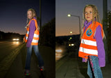Child wearing the Rolly Hi Vis Safety Vest while walking on a street at dusk with headlights in the background