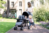 Safety 1st Teamy black tandem stroller on garden path with woman and two children