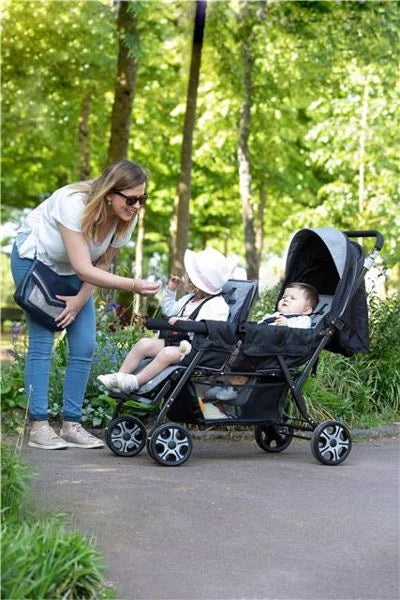 Safety 1st Teamy black tandem stroller in park with woman and two children