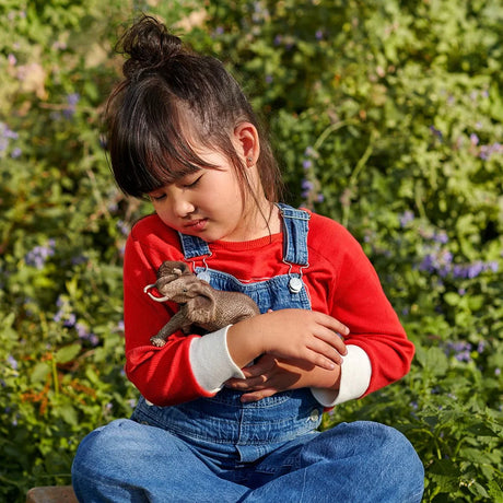 Child holding a grey Schleich elephant figure outdoors