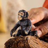 Schleich Baby Chimpanzee figure being held on a textured log