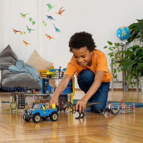 Schleich Brachiosaurus figure beside a blue toy vehicle and dinosaur playset while a child plays with other dinosaur figures