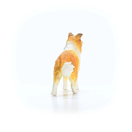 Rear view of the Schleich Collie figure showing its brown and white coat, four legs and raised white-tipped tail