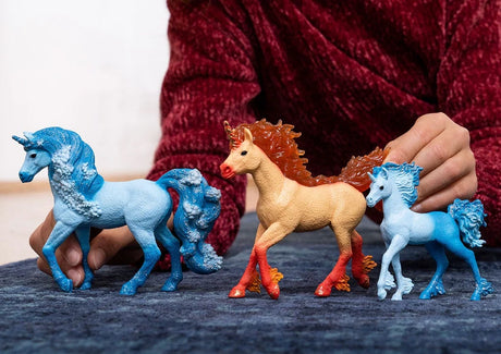 Schleich Elementa Fire Unicorn Stallion figure standing between two blue unicorn figures on a blue surface