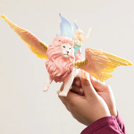 Hand holding the Schleich winged lion with the fairy seated on its back and both wings extended